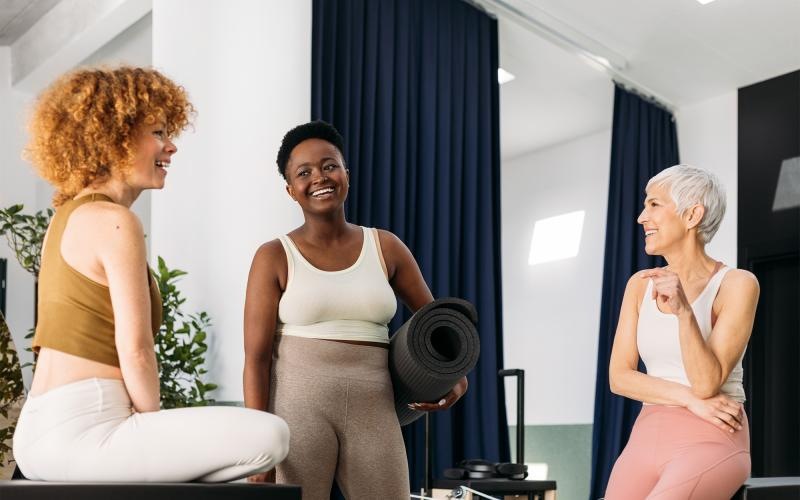 a person holding a yoga mat standing next to a person sitting on a chair