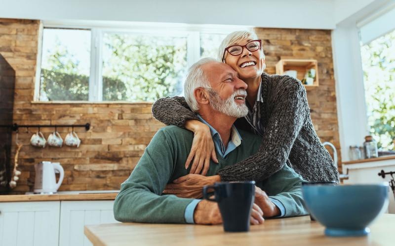 older couple hugging in their sun-filled kitchen